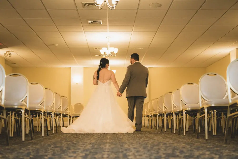 Bride and groom walking hand in hand through the ceremony room